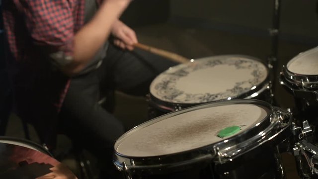 Long-haired drummers play drum kit in a dark room on a black background. Rock musician. Static plan. Wide angle