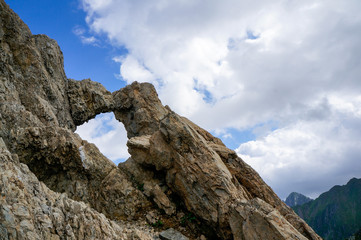 Fototapeta na wymiar Rock formation forming a window like shape with a view towards a blue cloudy sky in Fagaras, Carpathian Mountains, named The Window of the Dragons (Fereastra Zmeilor). Mountain peak landscape.
