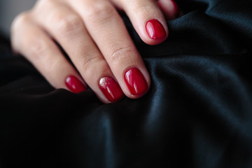 Gorgeous manicure, clssic red color nail polish, closeup photo. Female hands over dark fur background