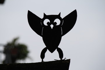 wrought iron owl leaning on a wood