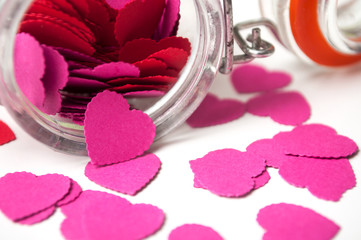 closeup of paper heart falling  from glass container on white background - valentine's day concept