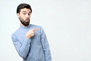Stylish handsome young hispanic man pointing aside.