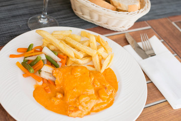 Salmon with prawn sauce served with french fries and vegetable