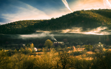 Smoke from the kitchen chimney over the autumn village in infrared