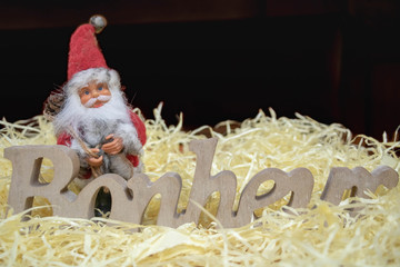 Père Noël et le mot Bonheur  écrit en français en bois sur fond noir - sentiment de bonheur à Noël