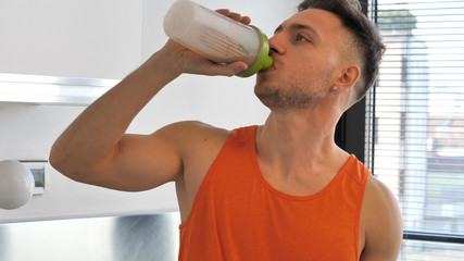Young man drinking a healthy smoothie drink or a protein shake from blender or shaker