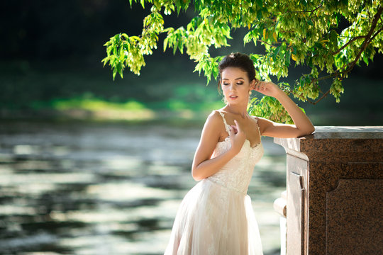 fashion photo of beautiful woman with dark hair in luxurious wedding dress posing outdoor.
