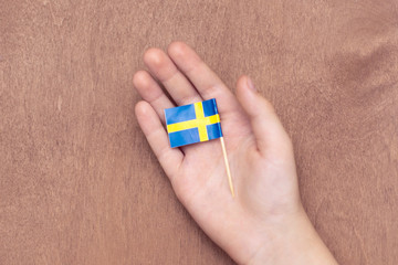 Swedish flag in child's hand on wooden background.12 December 2018.