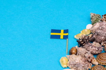 Swedish flag next to a beautiful seashell on a blue background.12 December 2018