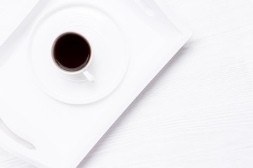 White cup of black coffee on a white wooden background. New life chapter concept
