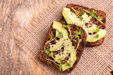 Healthy rye toasts with avocado, radish sprouts and sesame