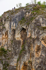 Two young men sitting on the rocks near Prohodna Cave, Iskar Gorge, Stara Planina, north central Bulgaria, picture from below