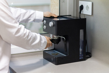 Man holding a coffee handle in a coffee machine on a table