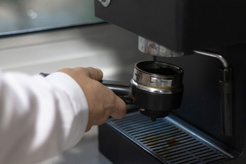 Man holding a coffee handle in a coffee machine on a table