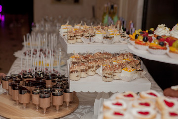Different fruit desserts with fruits in glasses on the table. Restaurant presentation, food, party concept