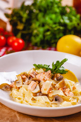 Pasta with salmon and mushrooms on white plate. Close up