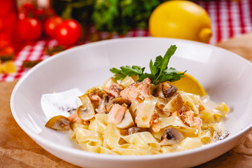Pasta with salmon and mushrooms on white plate. Close up