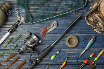 Flat lay composition with fishing equipment on wooden background