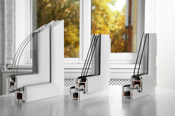 Samples of modern window profiles on table indoors. Installation service