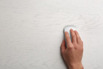 Man using computer mouse on wooden table, top view. Space for text