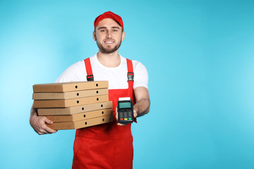 Smiling courier with pizza boxes and payment terminal on color background. Space for text