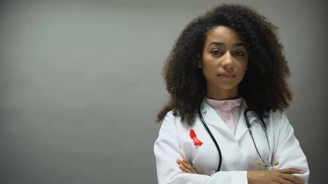 Afro-American female doctor with red ribbon, international AIDS awareness sign