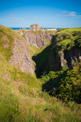 Panorama of a cliff with ancient castle in a bay with blue sky and white clouds in Dunnottar Castle, near Stonehaven, Aberdeenshire