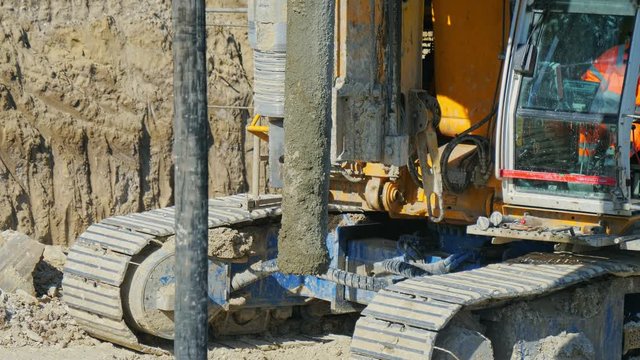 Heavy big excavator break trough holes for concrete colones for new road in construction site. Building a new streets in urban area, city town