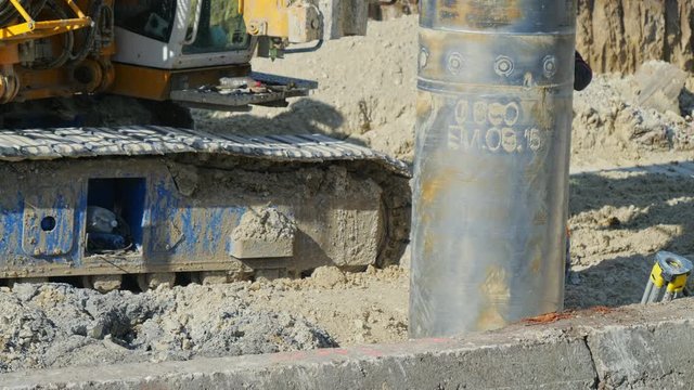 Heavy big excavator break trough holes for concrete colones for new road in construction site. Building a new streets in urban area, city town
