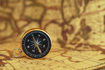 Fototapeta na wymiar Compass on blur vintage map background, retro color tone, direction journey planning concept, blank space, top view