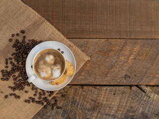 Cup of coffee with a biscotti on a rustic wooden background.