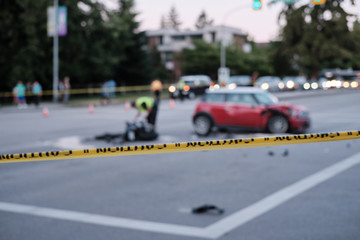 Accident of motorcycle and car at crossroad, blurred. Caution yellow police line in foreground
