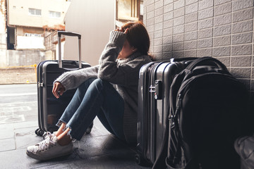 A woman sitting with feeling sad and lost while traveling with a lot of baggages on the floor - obrazy, fototapety, plakaty