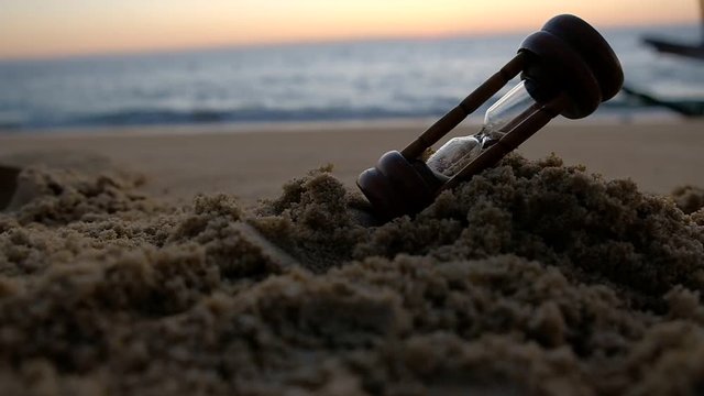 hourglass on a sand and sunset background. feeling end time