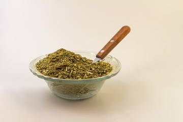 Glass pot with ground yerba mate on white background.