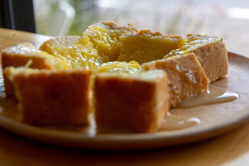 Sliced toast bread with butter and sugar and condensed milk in wooden plate .