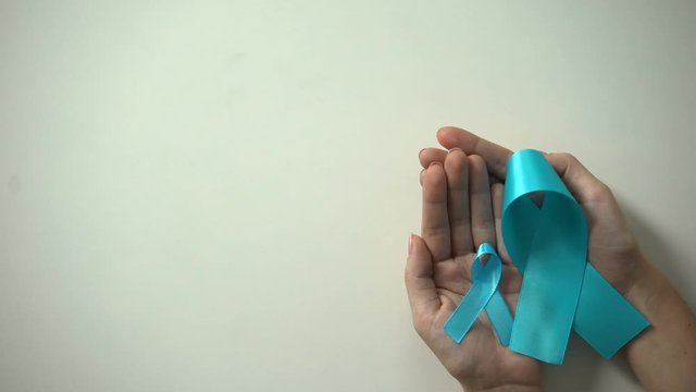 Big and little blue ribbons in hands, prostate cancer awareness day, precaution