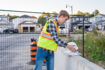 Young construction worker putting on his safety gear at a job site.
