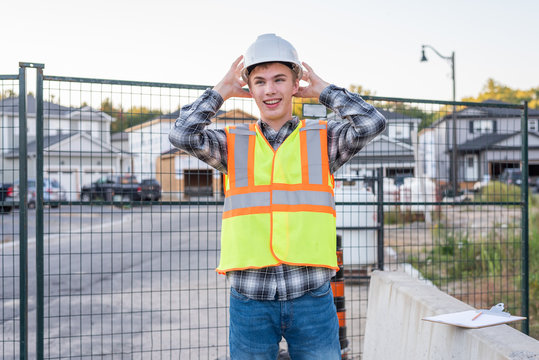 Young Construction Worker Putting On His Safety Gear At A Job Site.