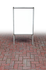 A blank advertisement A-board on a brick floor.