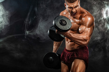 Fototapeta na wymiar Brutal strong muscular bodybuilder athletic man pumping up muscles with dumbbell on black background. Workout bodybuilding concept. Copy space for sport nutrition ads.