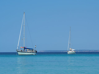 Colonia Sant Jordi, Ses Salines, Spain. Amazing view of the boats with a turquoise sea close to the charming beach of Es Trencs. It has earned the reputation of Caribbean beach of Mallorca