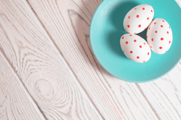 Three decorated Easter eggs on a turquoise plate on a white background.