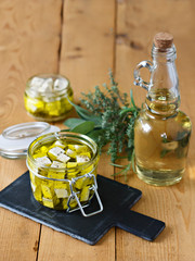 Obraz na płótnie Canvas Marinated feta in a glass jar, spices and olive oil on a wooden background