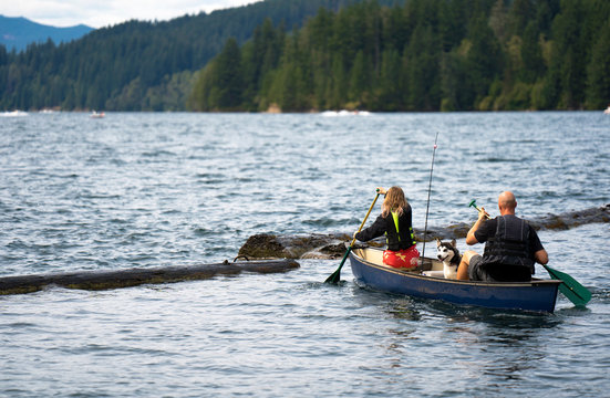 Father and daughter with oars went fishing with husky dog rowing in kayak on the waves of Lake Merwin in Washington