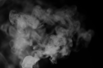 White smoke on a black background. Texture of smoke. Clubs of white smoke on a dark background for an overlay