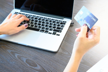 Young asian woman holding credit card and using laptop computer to shopping on line at cafe, business and technology concept, digital marketing, casual lifestyle