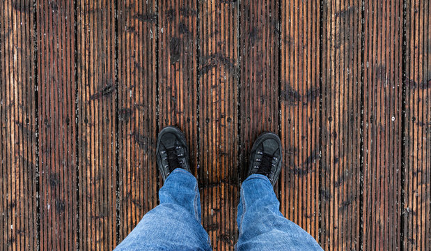 Person in Jeans steht auf Holzboden