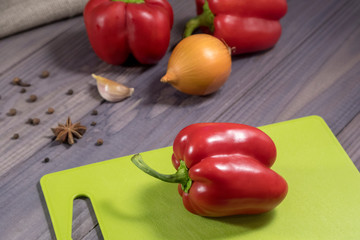 Three sweet red peppers with onion on the table. Process of cooking.