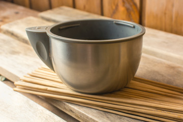 Mug from a thermos on a bamboo broom in a bath